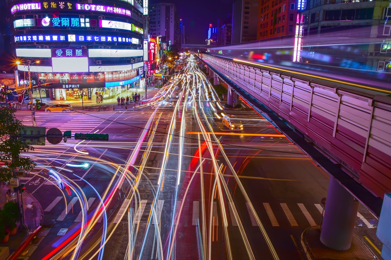 services-04 Dynamic city intersection with colorful light trails and neon lights at night, showcasing urban motion and energy.